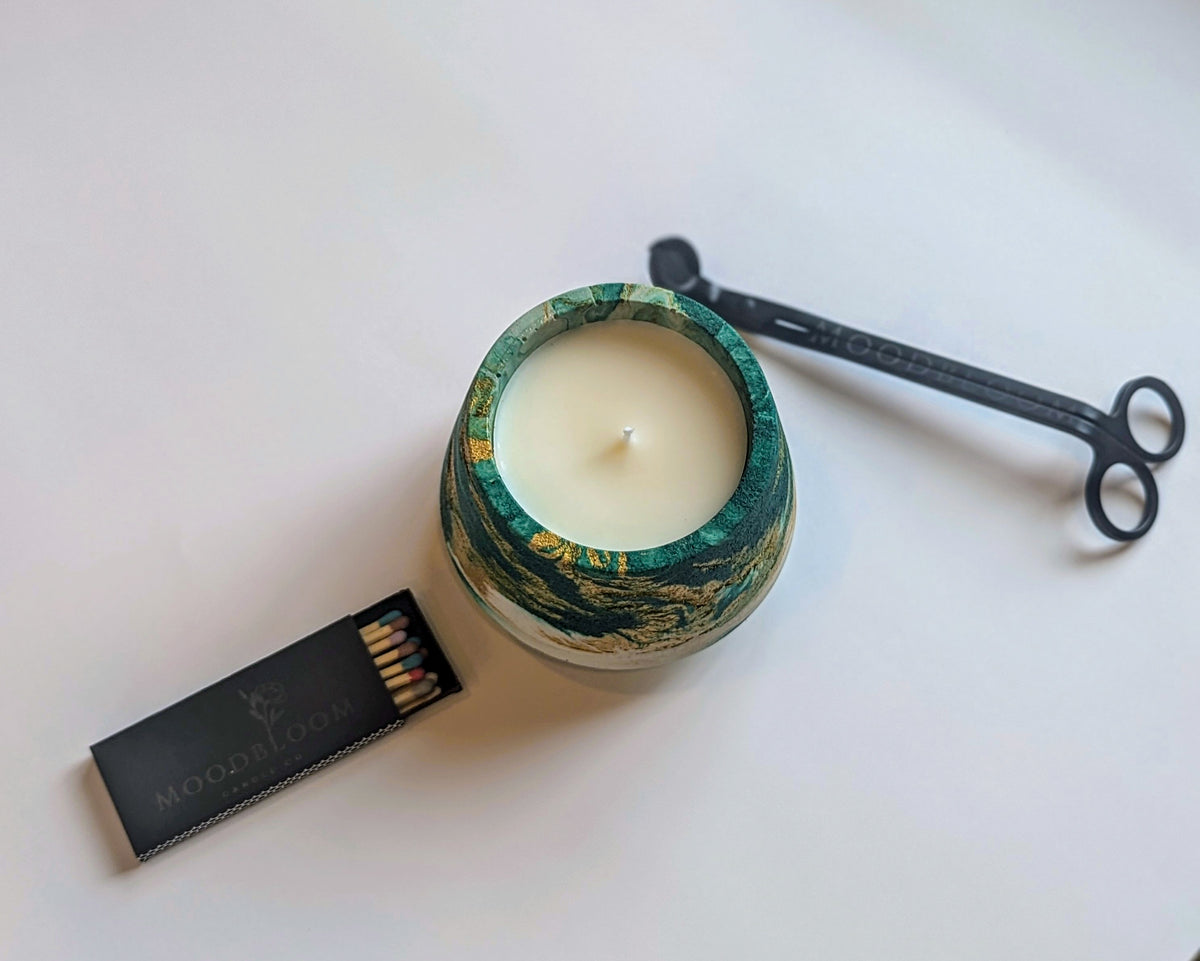 green and gold swirled concrete candle with matches and a wick trimmer